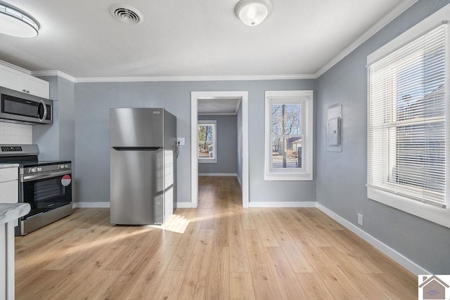 kitchen with tasteful backsplash, stainless steel appliances, white cabinets, light hardwood / wood-style floors, and crown molding