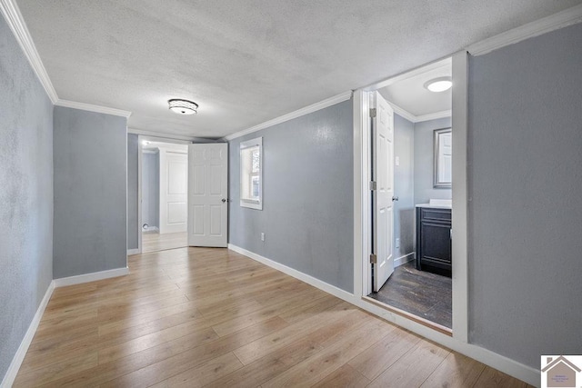 spare room featuring ornamental molding, light hardwood / wood-style floors, and a textured ceiling