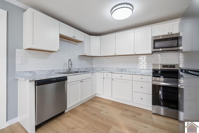 kitchen with light hardwood / wood-style flooring, stainless steel appliances, light stone countertops, white cabinets, and sink