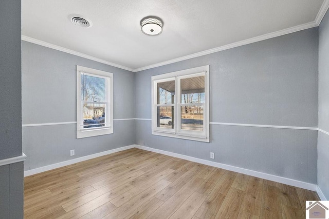 unfurnished room featuring ornamental molding, a wealth of natural light, and light hardwood / wood-style flooring