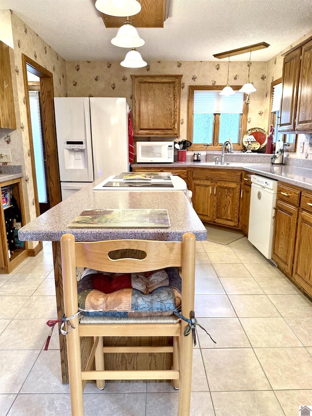 kitchen featuring light tile patterned floors, white appliances, brown cabinets, and pendant lighting