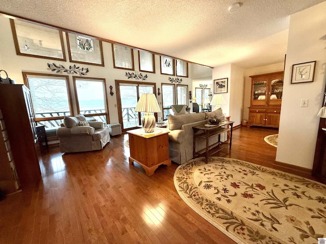 living area with vaulted ceiling, a textured ceiling, baseboards, and wood finished floors