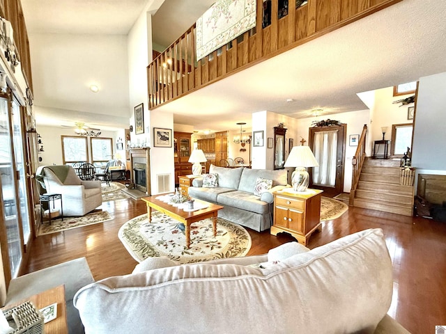 living room with visible vents, a towering ceiling, dark wood finished floors, stairway, and a glass covered fireplace