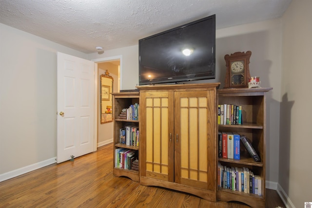 living area with hardwood / wood-style flooring and a textured ceiling