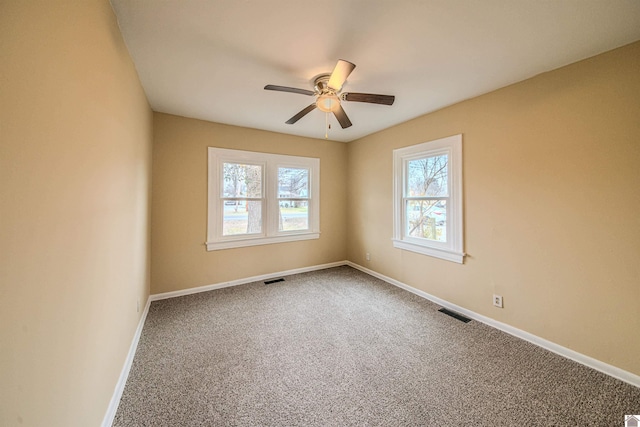 spare room featuring carpet, visible vents, baseboards, and a ceiling fan