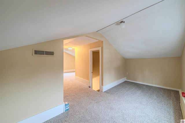 additional living space featuring vaulted ceiling, carpet, visible vents, and baseboards