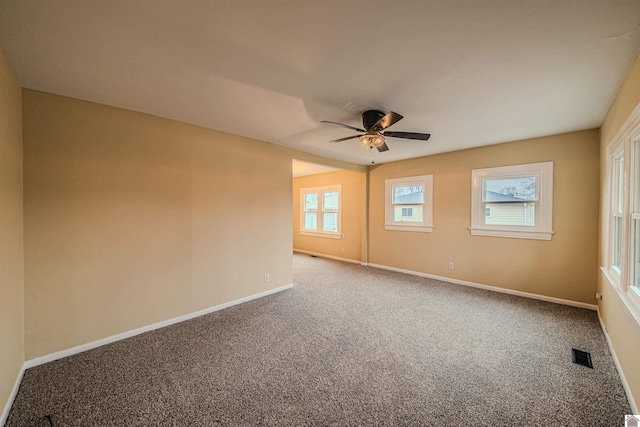 carpeted spare room featuring baseboards, visible vents, and a ceiling fan