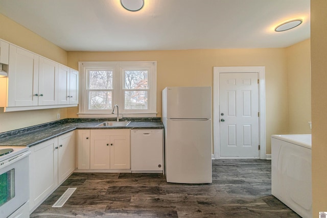 kitchen featuring white appliances, dark countertops, a sink, and white cabinetry