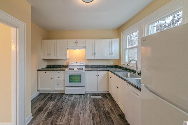 kitchen with dark countertops, white cabinetry, a sink, white appliances, and under cabinet range hood