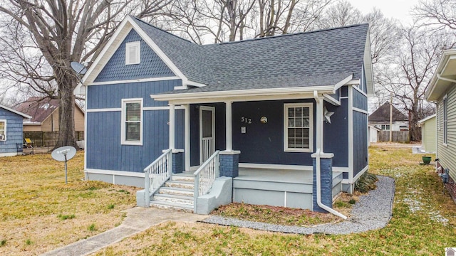 view of front facade featuring a front lawn, a porch, and roof with shingles