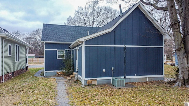 view of home's exterior with roof with shingles, a yard, and central AC unit