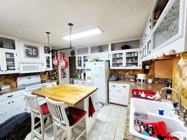 kitchen featuring pendant lighting, white appliances, glass insert cabinets, and white cabinets