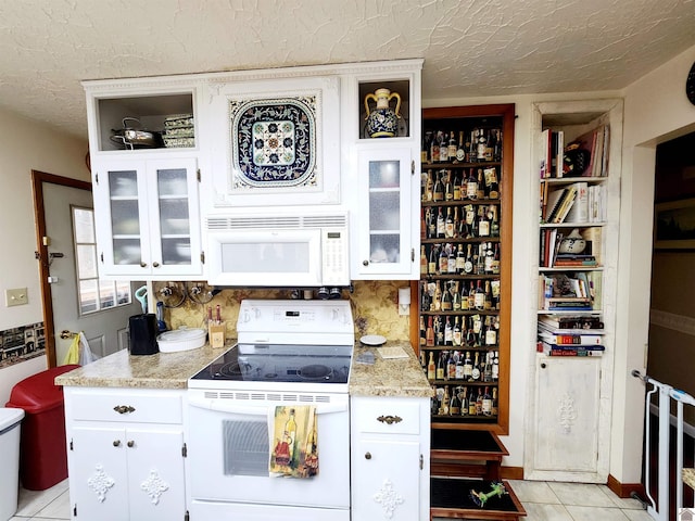 kitchen with a textured ceiling, white appliances, glass insert cabinets, and white cabinetry