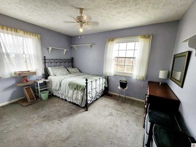 bedroom with light carpet, a ceiling fan, baseboards, and a textured ceiling