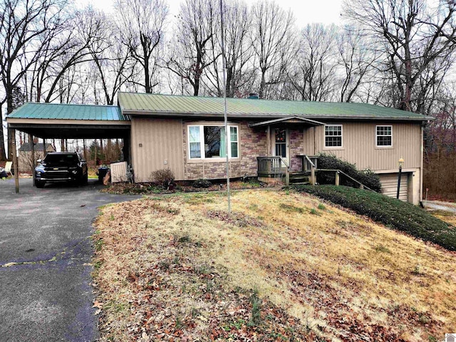 view of front of house with an attached garage, metal roof, an attached carport, stone siding, and driveway