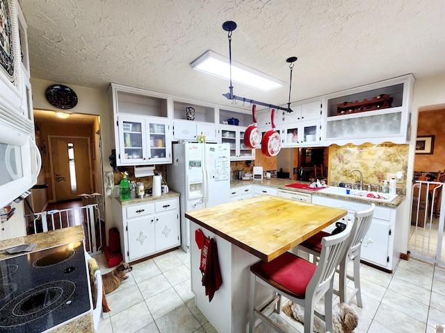 kitchen featuring glass insert cabinets, white cabinetry, decorative light fixtures, and open shelves