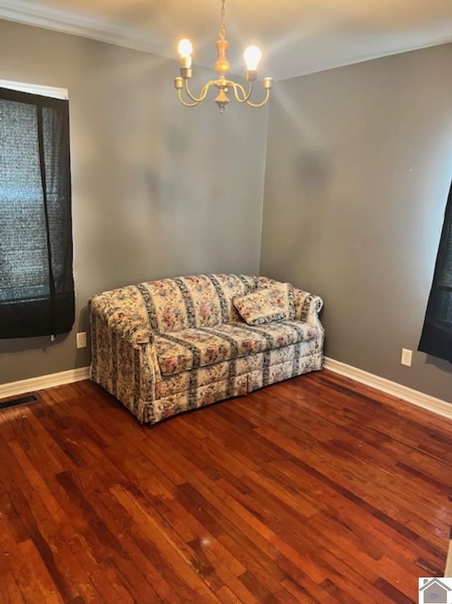 living room with visible vents, a notable chandelier, baseboards, and wood finished floors