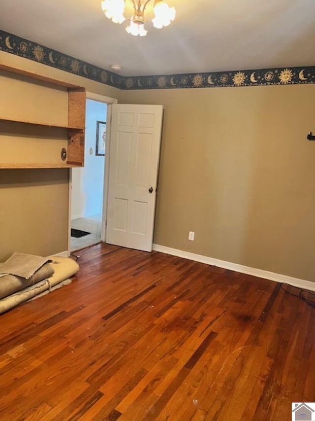 unfurnished bedroom with a chandelier, baseboards, and wood finished floors