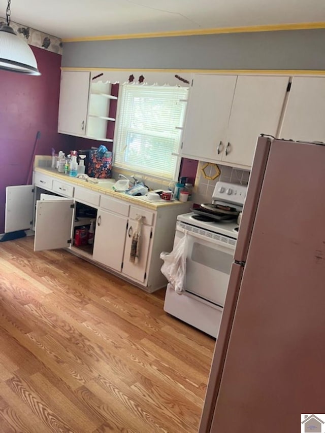 kitchen featuring decorative light fixtures, white electric stove, light countertops, freestanding refrigerator, and white cabinetry