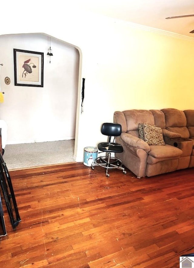 living area featuring ornamental molding, arched walkways, ceiling fan, and wood finished floors