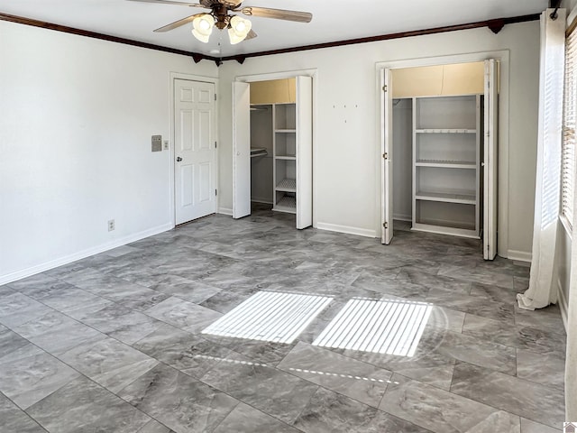 unfurnished bedroom with ornamental molding, ceiling fan, baseboards, and two closets