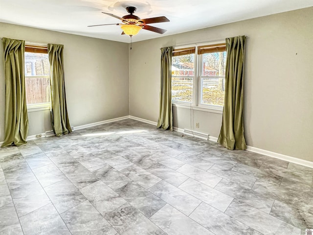 unfurnished room with ceiling fan, a wealth of natural light, and baseboards