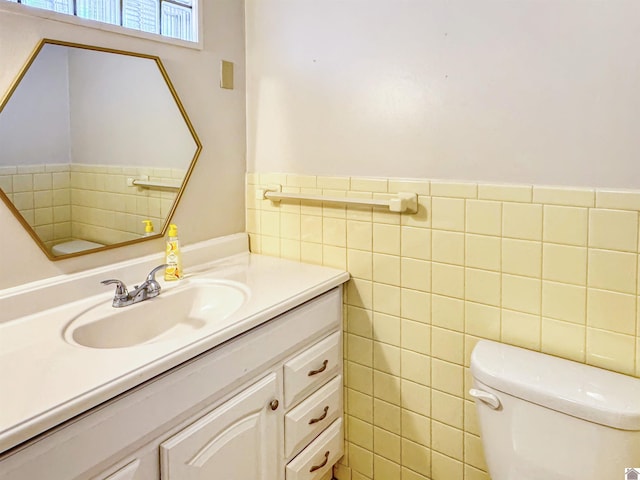 bathroom featuring wainscoting, toilet, tile walls, and vanity