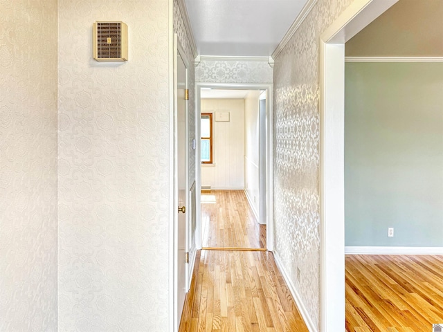 hallway featuring wallpapered walls, baseboards, ornamental molding, and light wood-style floors