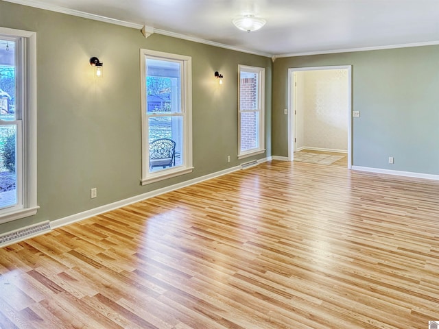 empty room with visible vents, crown molding, and light wood-style flooring