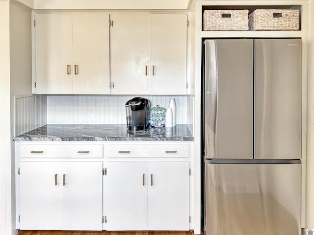 kitchen with white cabinets, stainless steel fridge, and backsplash