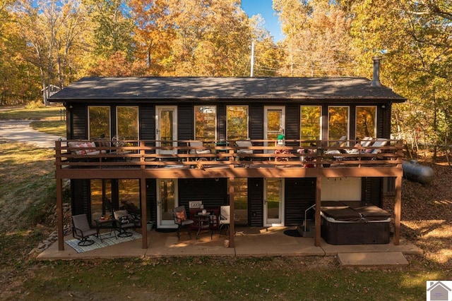 rear view of property featuring a patio, a hot tub, and a wooden deck