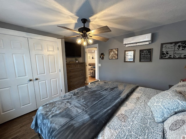 bedroom featuring a closet, dark wood-type flooring, ceiling fan, a textured ceiling, and a wall mounted air conditioner