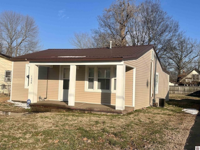 view of front of home featuring metal roof, central AC unit, a front yard, and fence