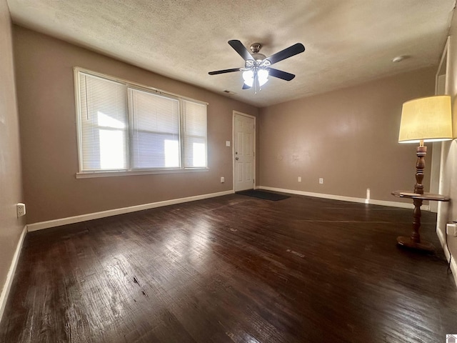 interior space featuring dark wood-type flooring, ceiling fan, a textured ceiling, and baseboards