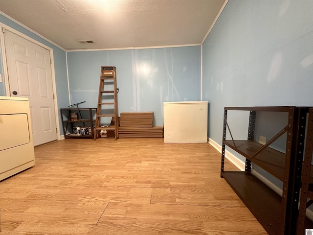 interior space featuring light wood-type flooring, visible vents, washer / clothes dryer, and ornamental molding