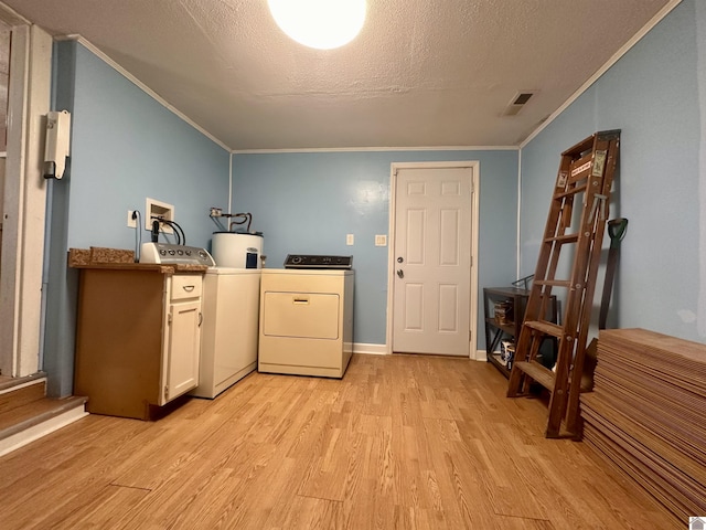 washroom with light wood finished floors, washing machine and clothes dryer, visible vents, cabinet space, and water heater