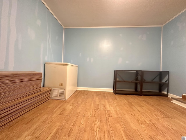 spare room featuring baseboards, crown molding, and light wood finished floors