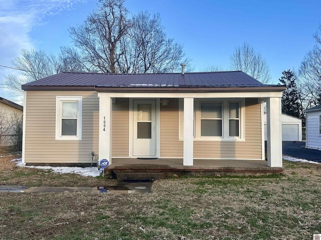 bungalow-style house featuring a garage, metal roof, and a porch