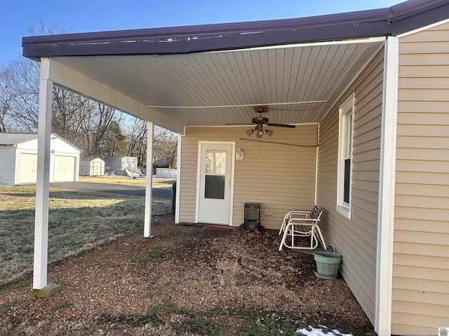 view of patio / terrace featuring a carport, a ceiling fan, and an outbuilding