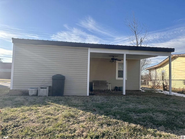 rear view of property featuring metal roof, ceiling fan, fence, and a lawn