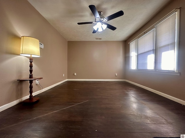 spare room featuring dark wood-style floors, a textured ceiling, visible vents, and baseboards