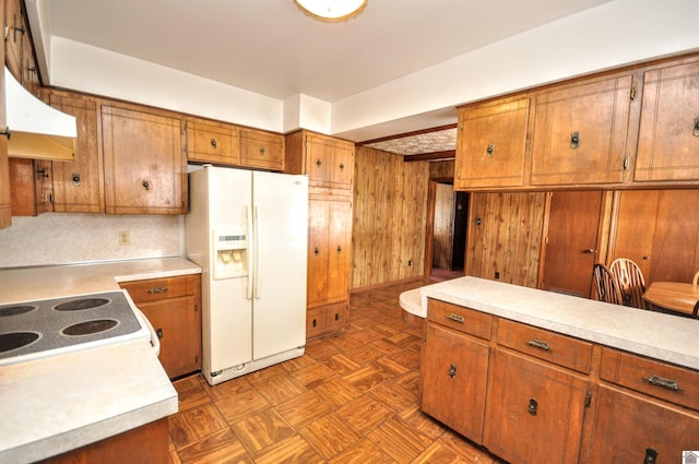 kitchen featuring white appliances, brown cabinets, wood walls, and light countertops