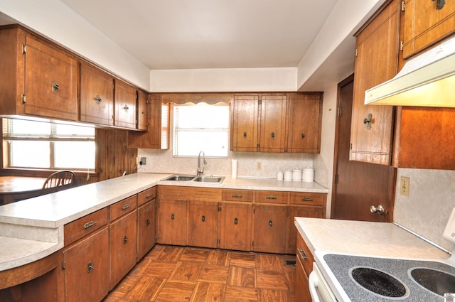 kitchen featuring tasteful backsplash, light countertops, brown cabinetry, electric range, and a sink