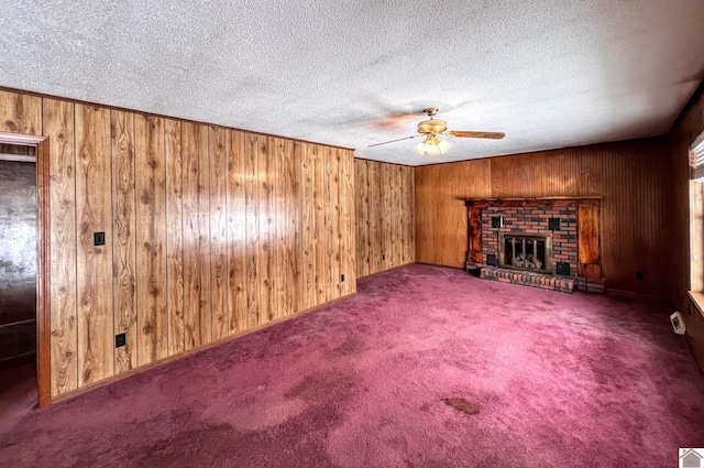 unfurnished living room featuring carpet, wood walls, a ceiling fan, and a textured ceiling