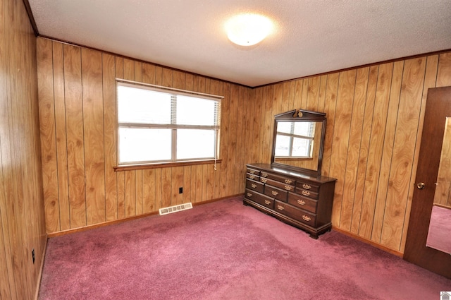 unfurnished bedroom with visible vents, dark carpet, a textured ceiling, and baseboards