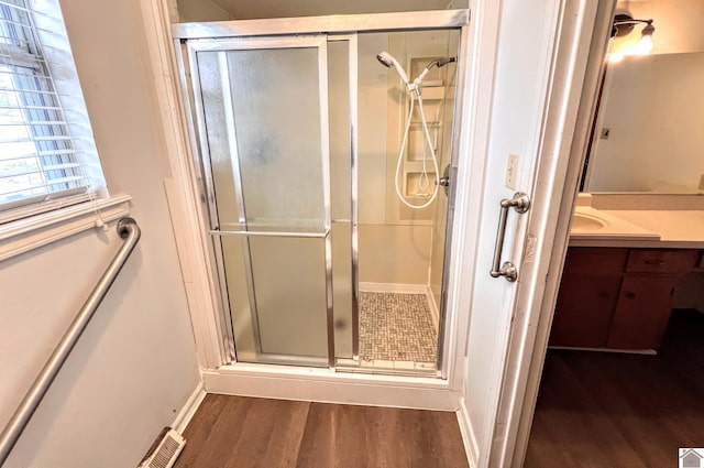 full bath featuring visible vents, a stall shower, wood finished floors, baseboards, and vanity