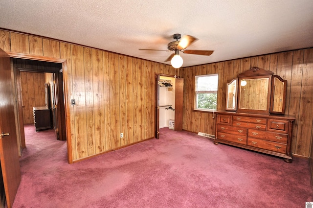 unfurnished bedroom featuring carpet flooring, visible vents, wood walls, and a textured ceiling