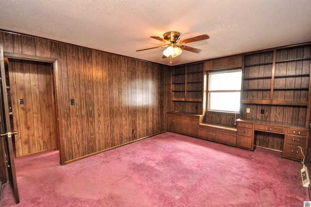 interior space featuring wood walls, a textured ceiling, and ceiling fan