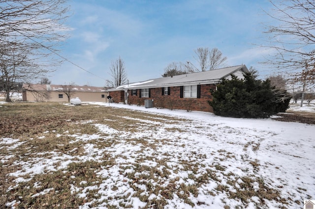 view of property exterior with brick siding, central AC, and metal roof