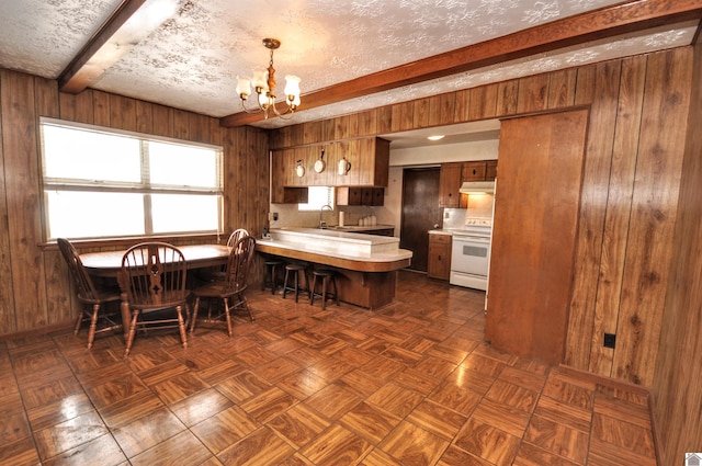 kitchen featuring beam ceiling, a notable chandelier, under cabinet range hood, white electric range oven, and light countertops